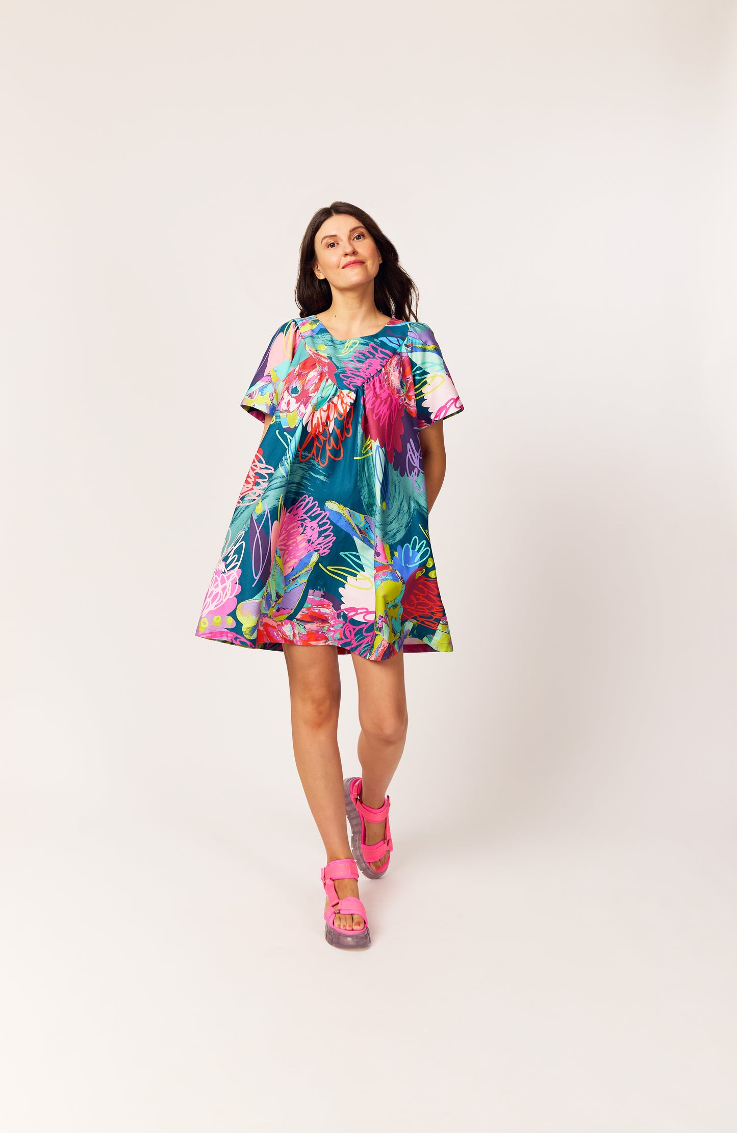 Lanya wearing The Debut Dress in Protea Collage print – bold organic cotton mini with teal base, collage floral pattern design, painterly details and pops of neon.