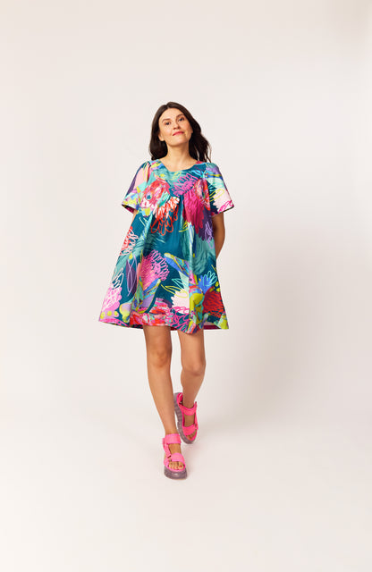 Lanya wearing The Debut Dress in Protea Collage print – bold organic cotton mini with teal base, collage floral pattern design, painterly details and pops of neon.